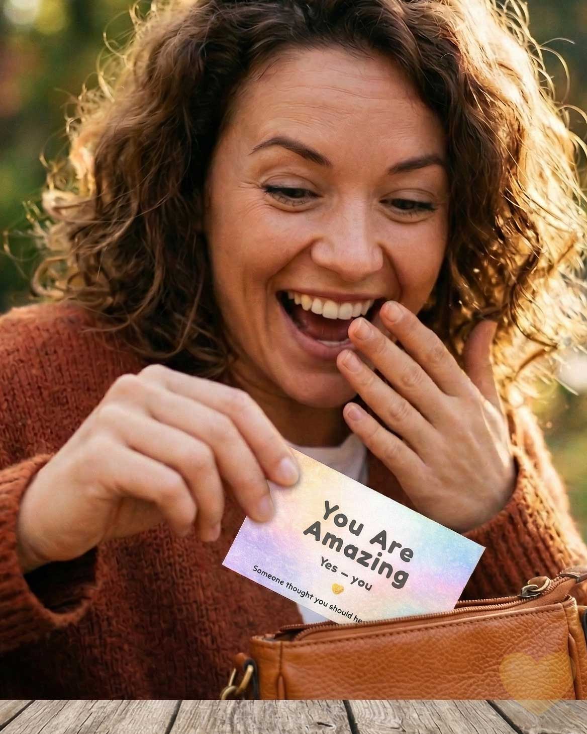 Woman holding a card that says 'You Are Amazing' outdoors