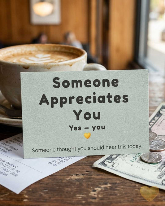 Card reading 'Someone Appreciates You' on a table with a coffee cup and money.